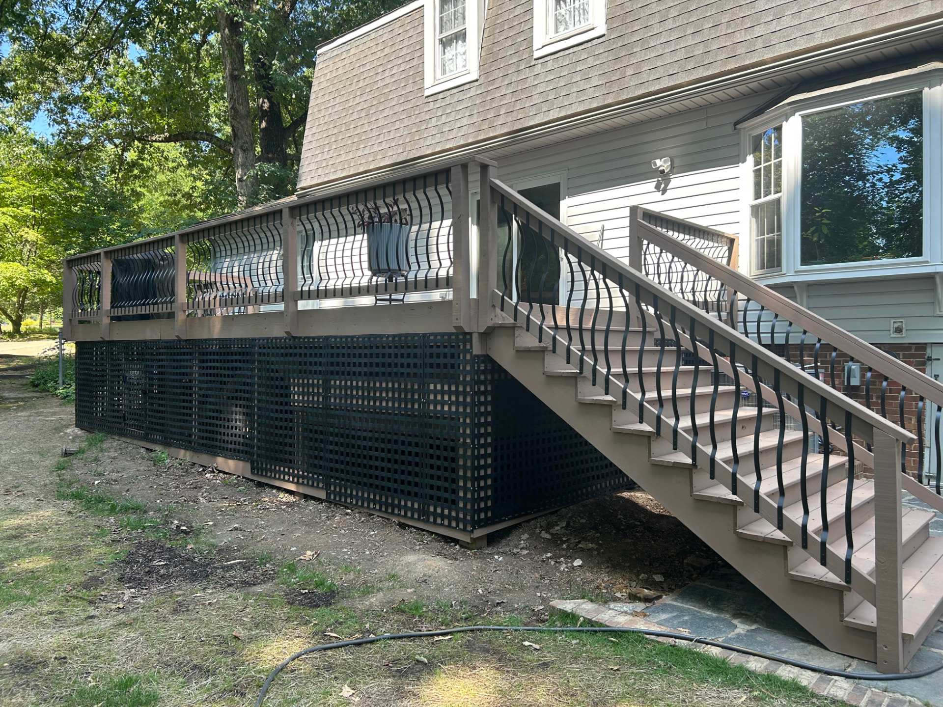 Stained raised wood deck with stairs and black lattice skirting